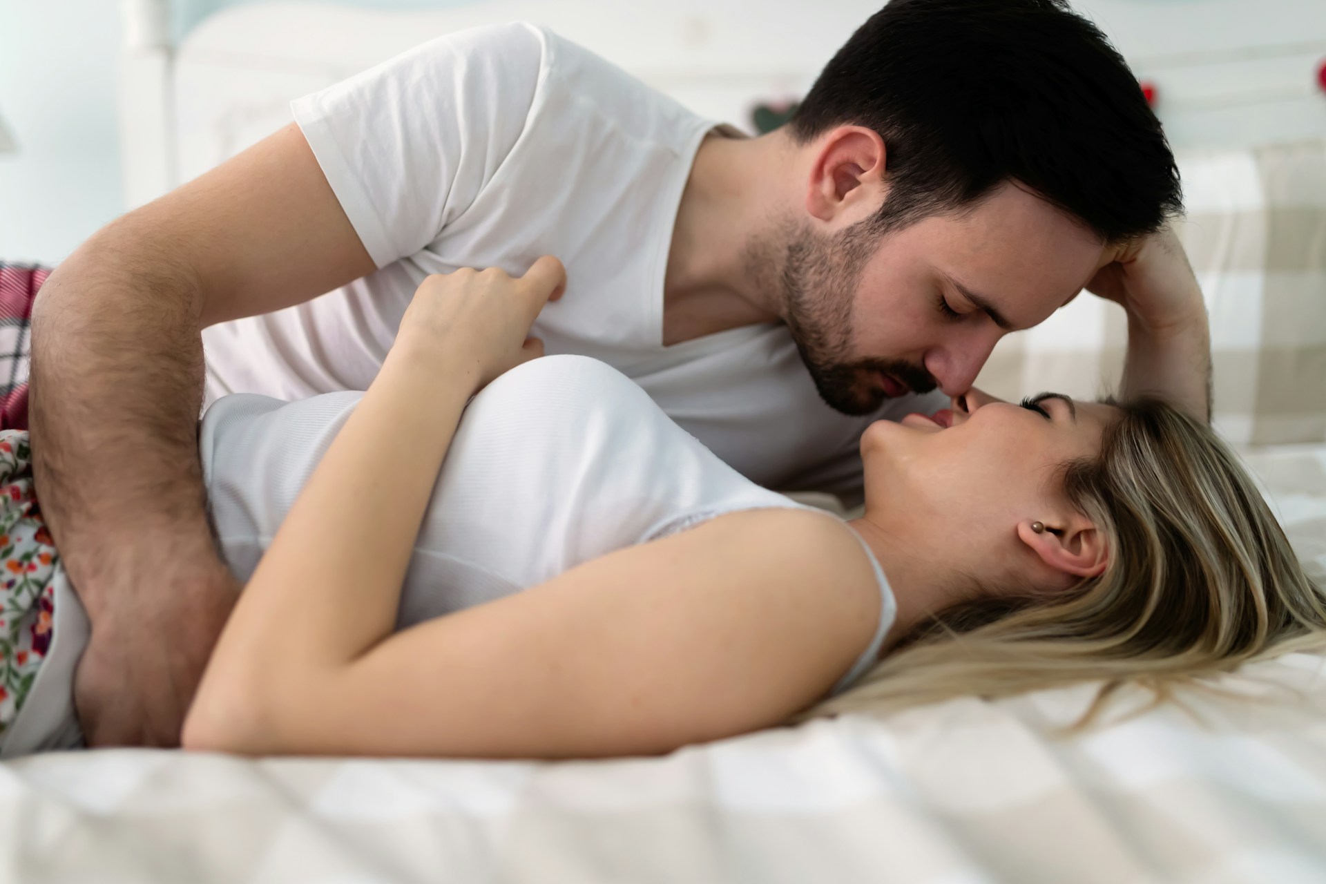 **SEO alt text:** `Couple kissing in bed while considering friends with benefits with an ex after a breakup`