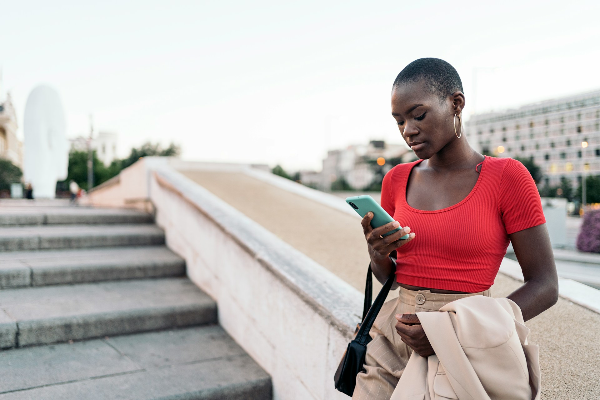 Woman looking at a smartphone after receiving a message from an ex, illustrating how to respond when your ex asks how you are.
