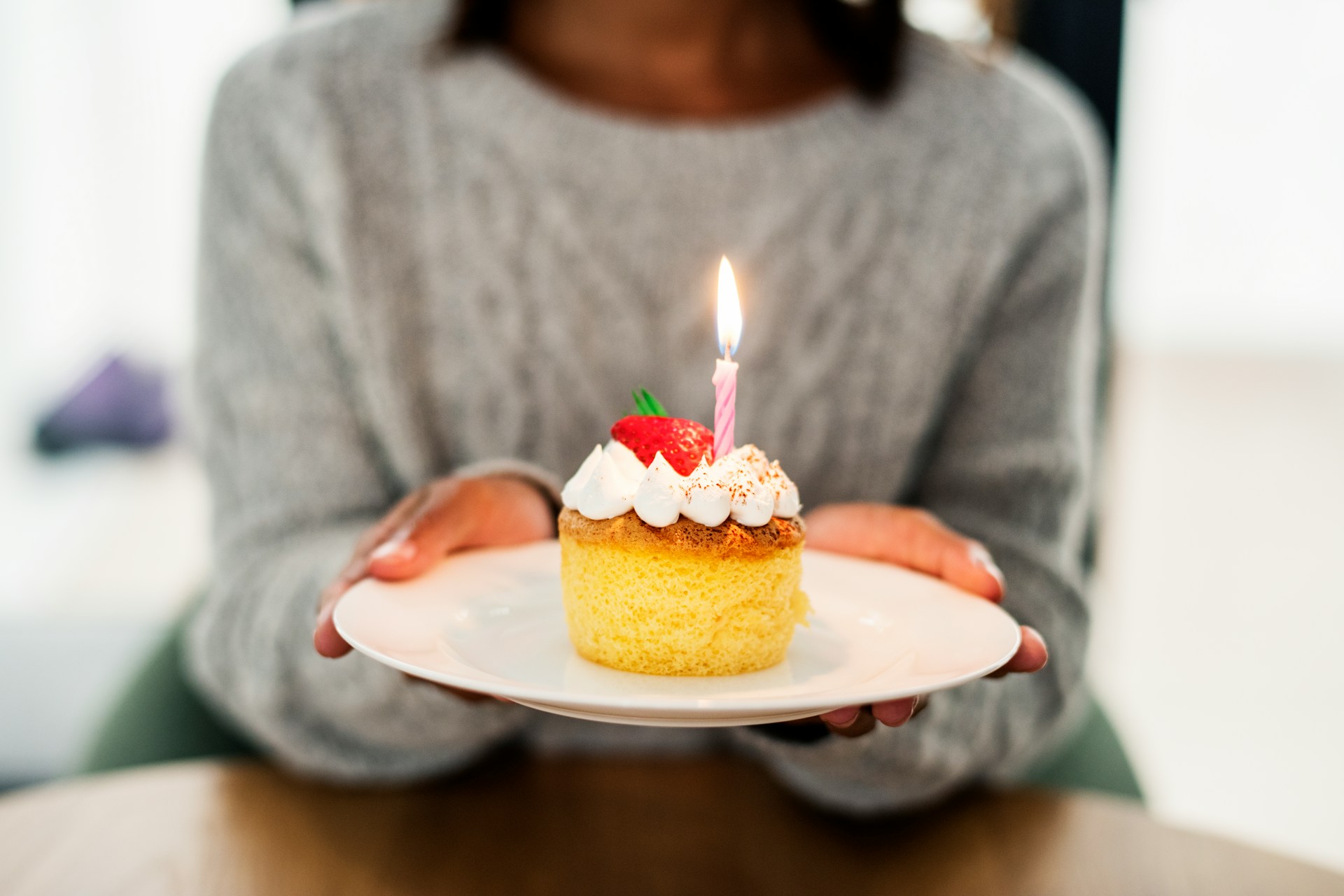 Woman holding a small birthday cake with a candle for a meaningful long-distance gift