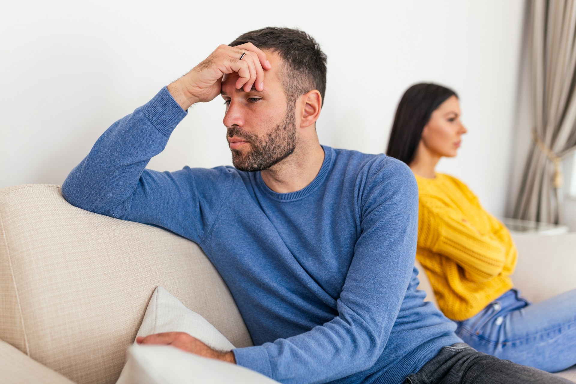 couple sitting distant on sofa represtingin traum bond relationship.