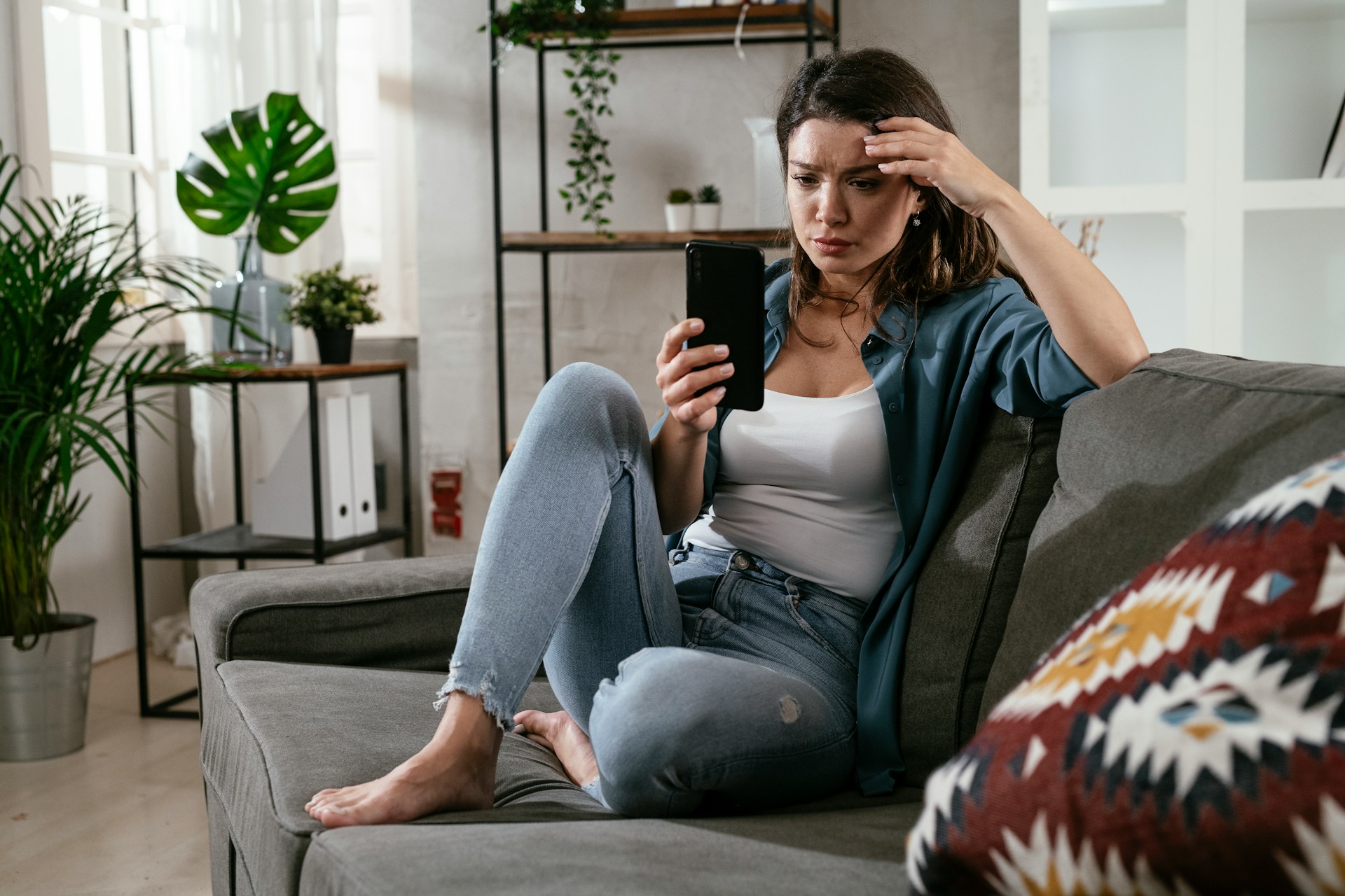 Woman checking her phone while sitting at a café table, representing dating, texting, first dates and early relationship interest.